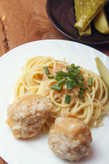 Spaghetti pasta with meatballs with green onion on wooden background