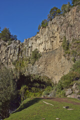 Colourful cliffs rising above a grassy plain on the entry to Laguna de Laja National Park in the Bio Bio region of Chile.