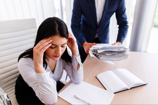 Businesswoman having headache for having too much work to get done from her boss