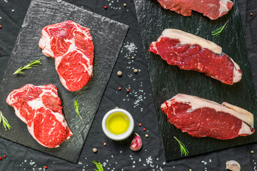 Beef cow steak meat with spices and herbs against black background