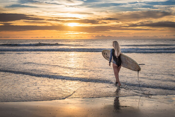 A surfer girl with longboard at the beach