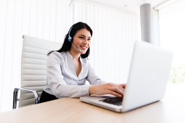 Attractive woman talking with customer at her work desk with headset