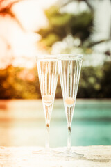 Two glasses of prosecco cocktail with orange berry at the edge of a resort pool. Concept of luxury vacation