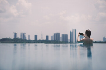 Beautiful girl in the pool with mobile phone on the background of the city of Malaysia Putrajaya. Putrajaya Skyscrapers
