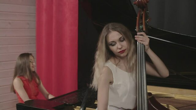 Two girls playing musical instruments. Piano and doublebass