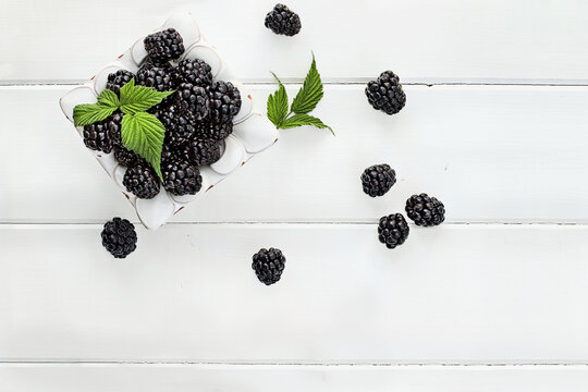 Overhead shot of fresh blackberry fruit over white wood table top. Room for copy space.