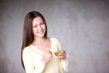 Beautiful young girl holding kiwi. Healthy food.