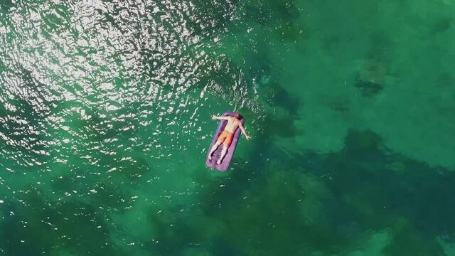 From above man people swims lay on inflatable matrass. Beautiful azure blue ocean water and sand beach. Triozerye Russia Primorsky krai. Aerial helicopter drone flight around. Summer sunny day. 4k
