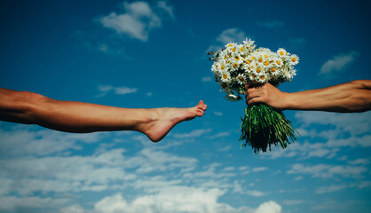 Sexy woman legs. Man hand holding flowers. Funny photo.