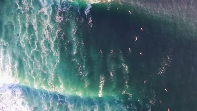 Top view aerial shot of surfers riding waves of turquoise ocean water