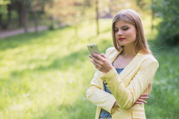 Beautiful young business woman with a mobile phone in the park.