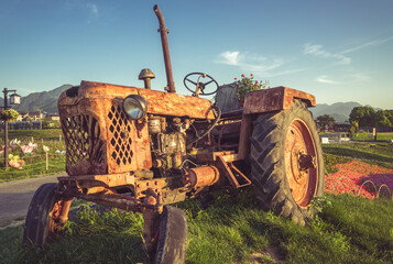 old Tractor parked on meadow against blue sky.