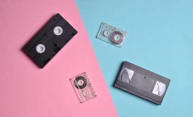 Audio cassettes and video cassettes are laid out on a multi-colored neon surface. Top view.
