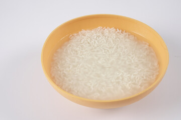 Soak rice in yellow bowl over white background