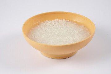 Soak rice in yellow bowl over white background