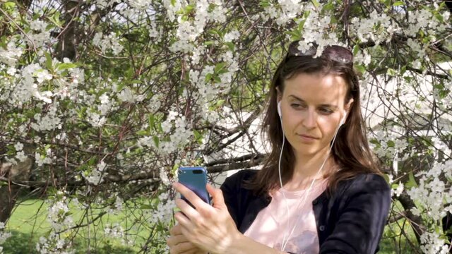 Young girl in blooming trees takes a selfie