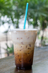 Iced coffee latte in takeaway cup on nature bokeh