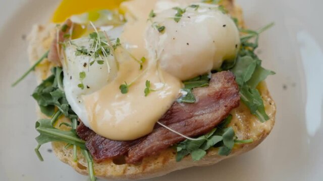 Eggs Benedict with bread and tomato on a plate with becon morning sandwich