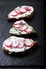 Sandwich with radish cheese on black slate background. Top view.