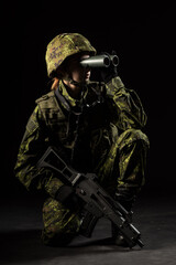 Portrait of armed woman with camouflage. Young female soldier observe with binoculars. Child...