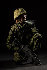 Portrait of armed woman with camouflage. Young female soldier observe with binoculars. Child soldier with gun in war, hause ruins background.  Military, army people concept