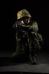 Portrait of armed woman with camouflage. Young female soldier observe with firearm. Child soldier with gun and binoculars in war, black background.  Military, army people concept