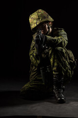 Portrait of armed woman with camouflage. Young female soldier observe with firearm. Child soldier with gun and binoculars in war, black background.  Military, army people concept
