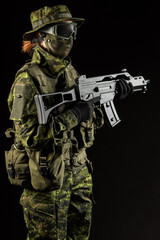 Portrait of armed woman with camouflage. Young female airsoft sniper observe with firearm. Soldier with gun in war, black background.  Military, army people concept