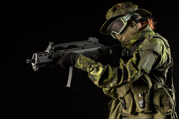 Portrait of armed woman with camouflage. Young female airsoft sniper observe with firearm. Soldier...