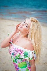 A beautiful european girl with a figure and the right features in a dress with a floral princess resting on the weekend enjoying the sun and a beautiful view of the water