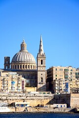 Fototapeta na wymiar View of St Pauls Anglican Cathedral and the Basilica of Our Lady of Mount Carmel seen from the Grand Harbour, Valletta, Malta.