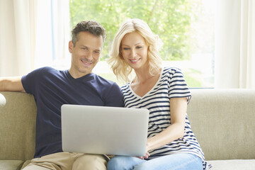 Browsing together. Shot of a happy mature couple relaxing on the couch using a laptop.