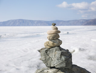 Stone tower on ice winter background. Baical landscape.