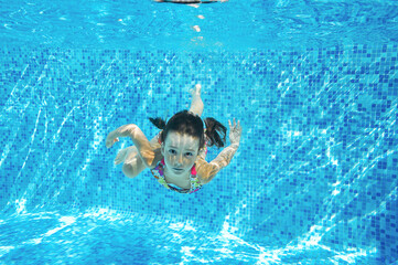 Child swims in pool underwater, happy active girl dives and has fun in water, kid fitness and sport on family vacation
