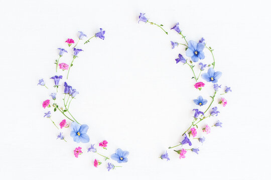 Wreath made of bell flowers, pansy flowers and pink flowers on white background. Flat lay, top view