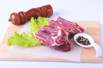 Raw beef edges, lettuce leaf, pepper grinder and spices on wooden desk isolated on white background from above and copy space. ready for cooking.