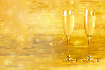 Two glasses of champagne on blurred golden background