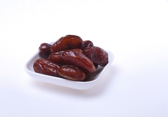 Delicious dried organic dates on bowl isolated over white background.