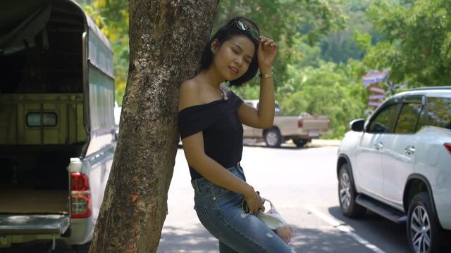 Young pretty Thai girl leans on tree in park 4k UHD (3840x2160)
