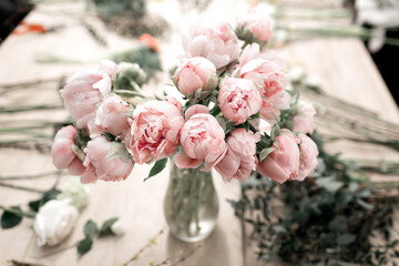 Pink peonies in vase on wooden floor and bokeh background - retro styled photo. soft focus. © malkovkosta