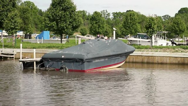Speedboat or bowrider covered with old tarp at marina