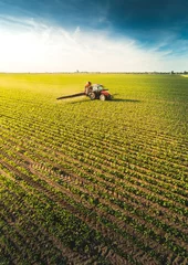 Crédence de cuisine en verre imprimé Tracteur Tractor spraying soybean field at spring