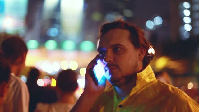 Businessman talking on mobile phone at night in the city with beautiful bokeh and heavy traffic on the road. hd, 1920x1080