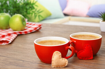 Cups of coffee with heart on wooden table