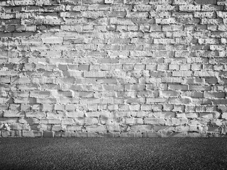White grungy brick wall and dark asphalt floor