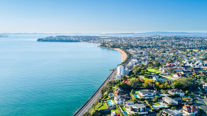 Obraz premium Aerial view on a road running along sea shore with residential suburbs on the background. Auckland, New Zealand.