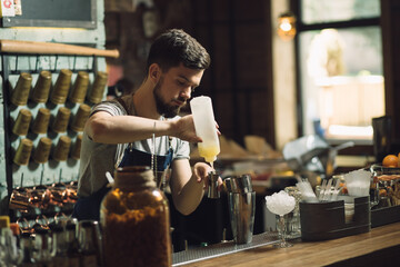 Young male bartender preparing an alcohol cocktail
