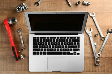 Laptop and tools for car repair on wooden table