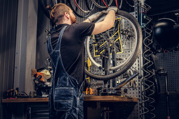 Fototapeta na wymiar Mechanic repairing bicycle wheel tire in a workshop.