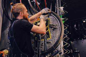 Obraz na płótnie Canvas Mechanic repairing bicycle wheel tire in a workshop.
